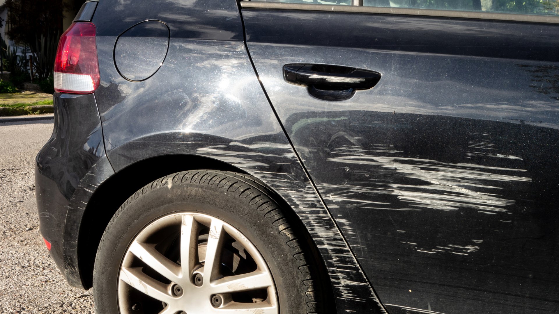 Black car with significant scratch marks on the rear door and fender.